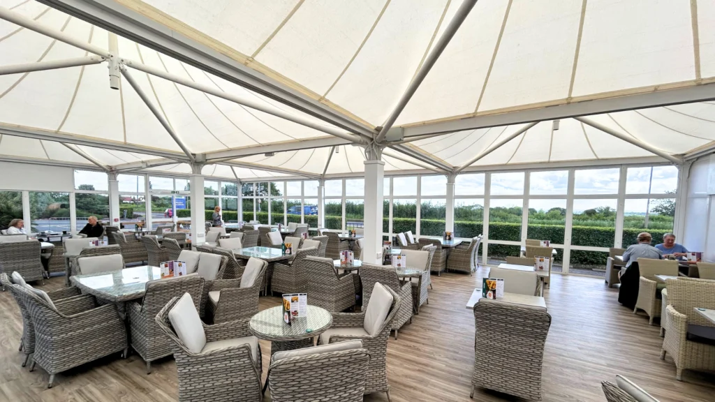 Spacious indoor seating area with wicker chairs and tables under a large canopy at Planters Brookfields Garden Centre.