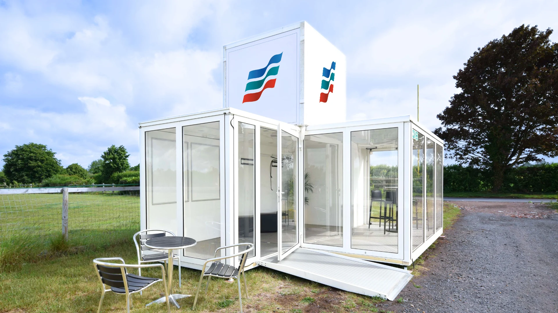 A modern white modular glass office structure with Showplace branding sits in a grassy field.