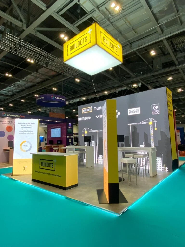 Buildots exhibition booth featuring a large yellow hanging sign and branded counters at a trade show.